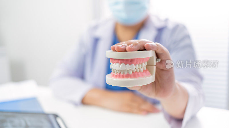 Dentist at dental clinic White healthy tooth with Dental model in oral surgeons discussing jaw x-ray on tablet medicine healthcare oral surgery concept.